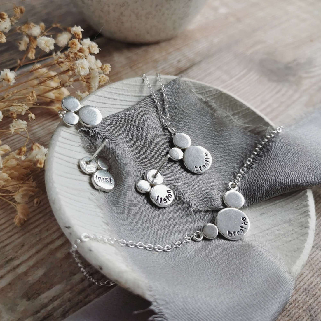 handmade jewellery of clusters of silver discs with positive affirmations and mantras stamped into the surfaces