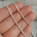 2mm silver curb chain for men draped over fingertips