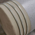2mm silver curb chain for men draped over a ceramic vase