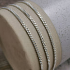 2mm silver curb chain for men draped over a ceramic vase