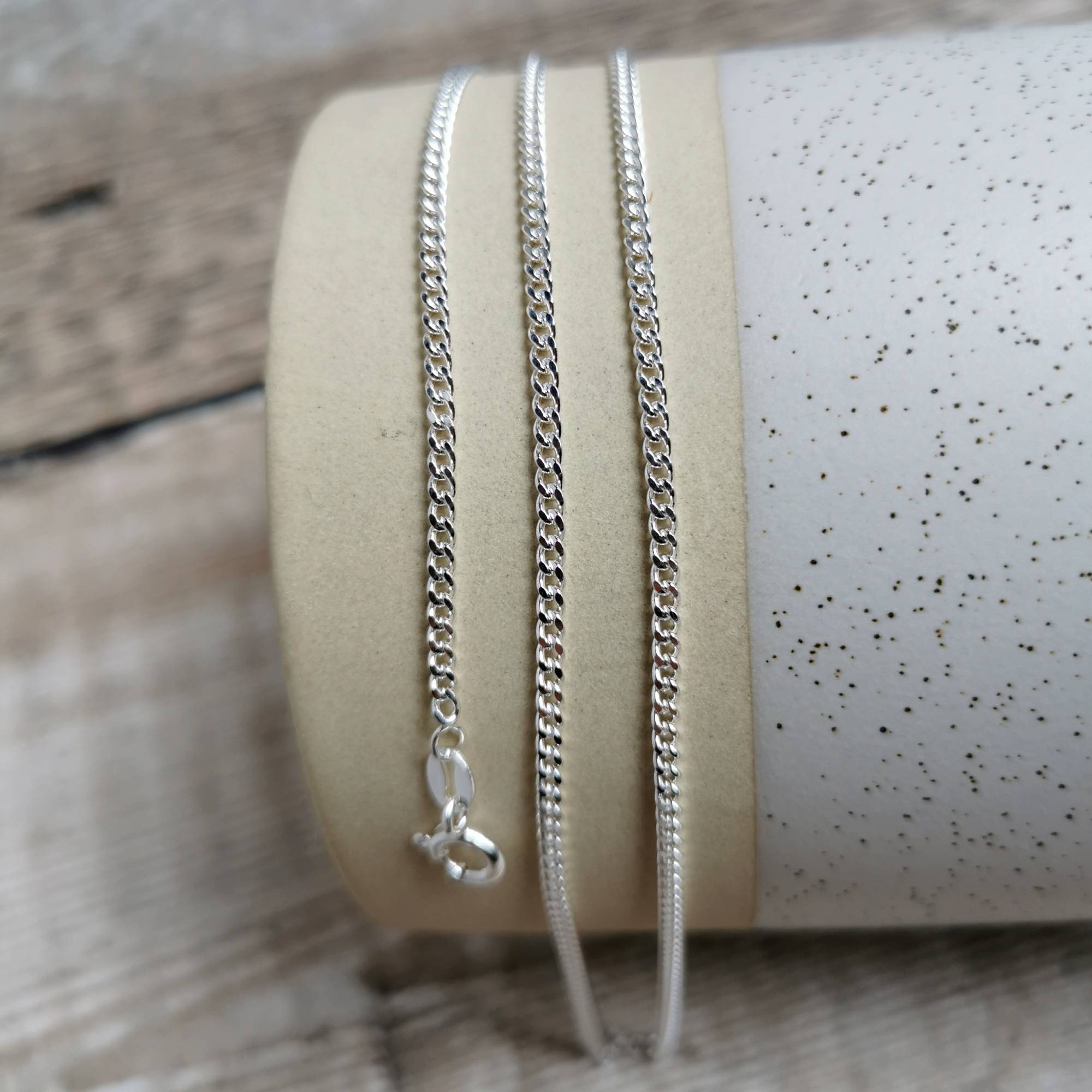 2mm silver curb chain for men draped over ceramic jug