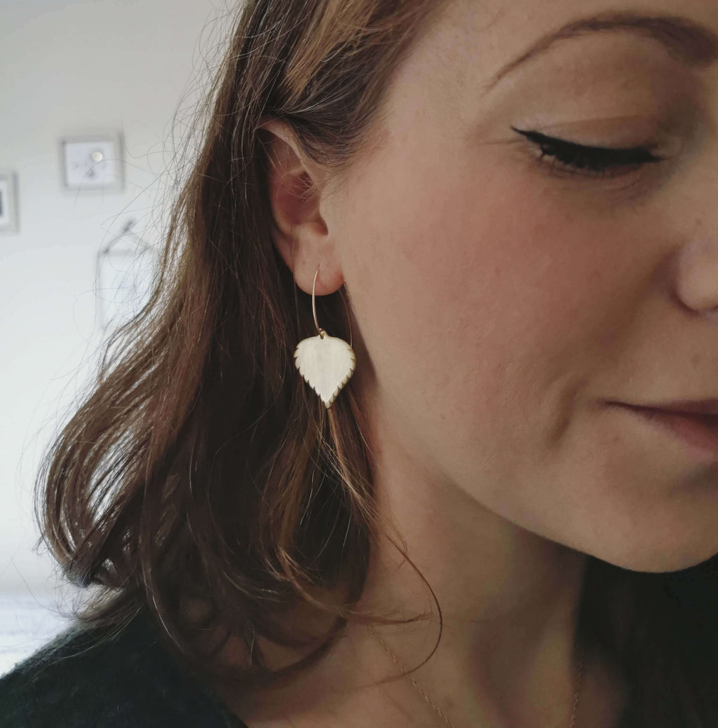 Close-up of a woman wearing heart-shaped earrings with a neutral background