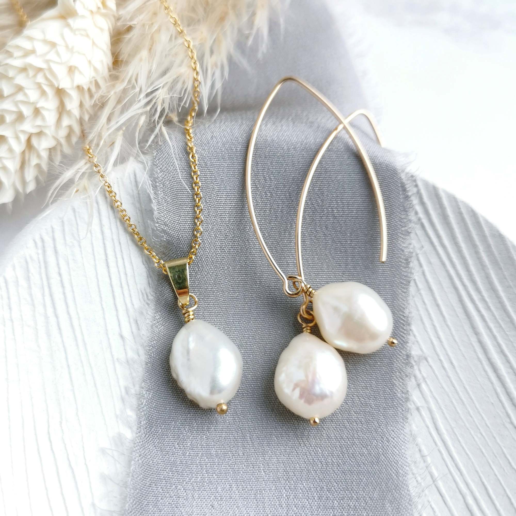 Pearl and gold necklace and earrings on a textured surface with a soft background