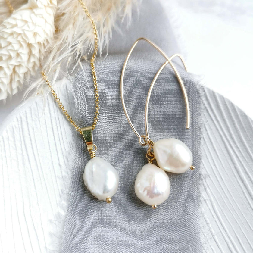 Pearl and gold necklace and earrings on a textured surface with a soft background