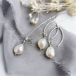 Pearl and silver necklace and earrings on a grey silk background with dried flowers