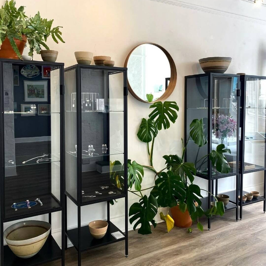 Modern interior with glass display cases, plants, and a round mirror.