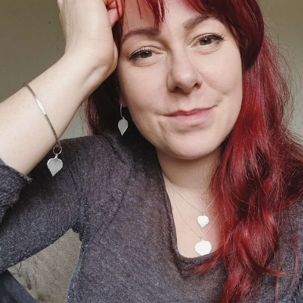 Cat Birch, a red haired young woman, wearing the silver birch leaf collection - handmade necklaces and earrings and bangle featuring silver birch leaves