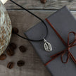 Necklace with a coffee bean pendant on a wrapped gift box with coffee beans around