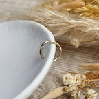 hammered Gold ear cuff on a white surface with dried flowers.