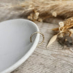 rope texture Gold ear cuff on a white ceramic plate with dried plants in the background