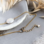Gold chain necklace with pearls on a gray surface