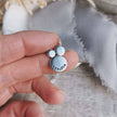 Silver pendant with 'breathe' engraving held between fingers against a textured fabric background
