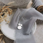 Silver necklace with circular shapes in a cluster on a textured fabric surface