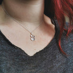 Necklace with a silver pendant worn by a woman with red hair, close-up shot.