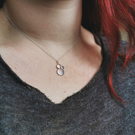 Necklace with a silver pendant worn by a woman with red hair, close-up shot.