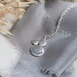 Silver necklace with 'breathe' stamped into the surface, on a textured fabric background