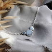 Silver necklace stamped with the word 'breathe' on a textured fabric background