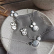 Silver necklaces, earrings and bracelet with hand stamped words as personal mini mantras and affirmations, displayed on a textured dish with grey silk
