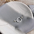 Silver and pearl necklace with a hammered circular pendant on a gray fabric surface