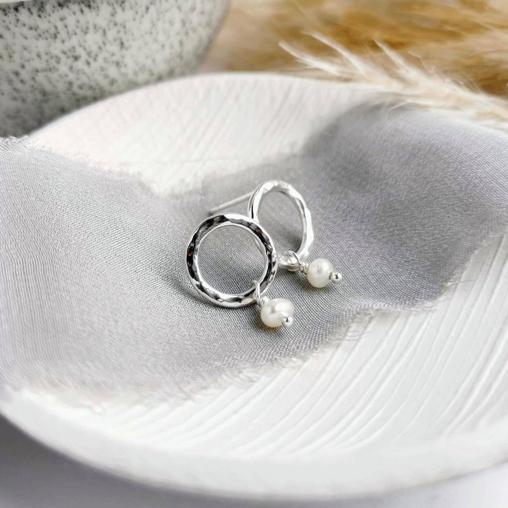 Silver studs with pearl details on a fabric background