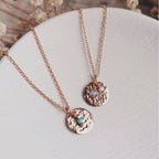 Two rose gold birthstone necklaces with hammered round pendants, one featuring a small turquoise bead for december and the other a small tanzanite bead as an alternative gemstone for december with a small pearl for june, displayed on a textured white surface.