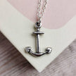 close up of a handmade silver anchor with silver chain on a pale pink and cream book cover