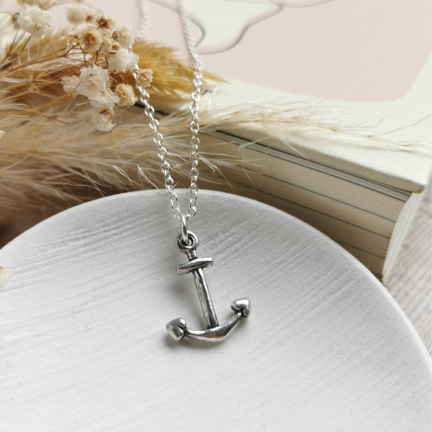 handmade silver anchor with silver chain on a white ceramic dish