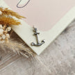 handmade silver anchor charm on a pale pink and cream book cover by Rupi Kaur