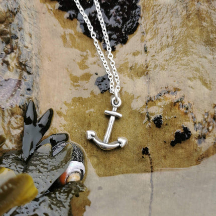 Silver anchor necklace on the edge of a rockpool in cornwall, uk