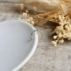beaded Silver ear cuff on a white ceramic plate with dried flowers in the background