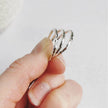 Hand holding three textured silver rings against a light background
