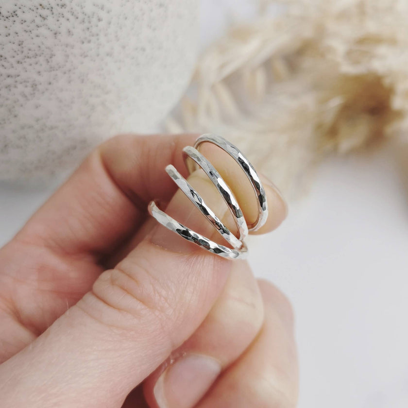 Hand holding hammered silver rings with a blurred background