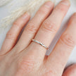 Minimal handmade textured silver ring worn on a finger with a soft background