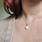 Person wearing a silver and pearl necklace by Cat Birch