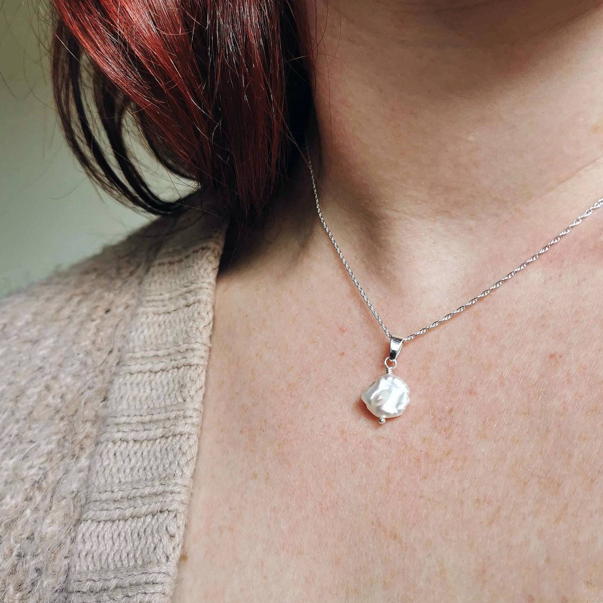 Person wearing a silver and pearl necklace by Cat Birch