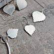 Handmade Silver leaf-shaped jewellery on a textured wooden surface