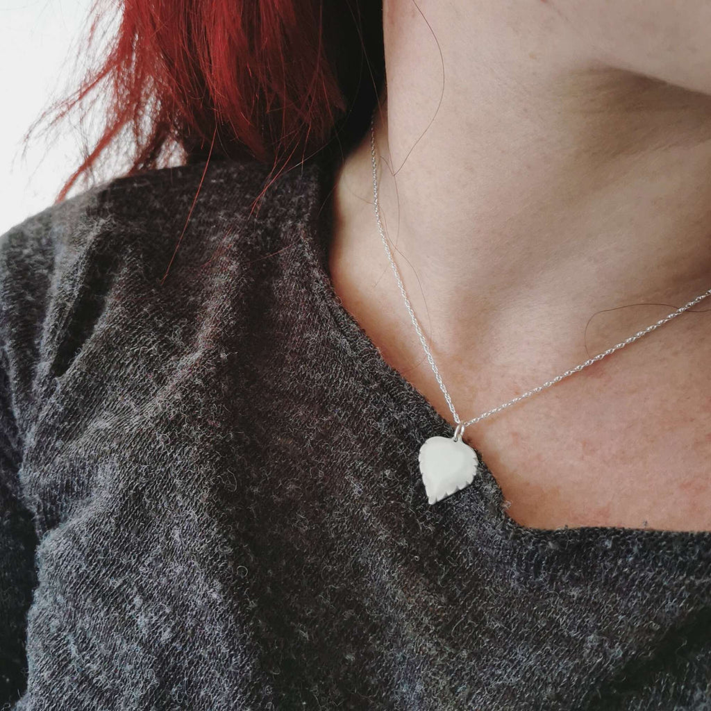 Young woman wearing a silver necklace with a birch leaf-shaped pendant
